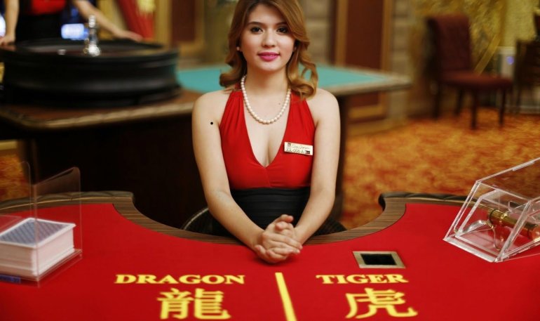 Симпатичная рыжеволосая девушка дилер ждет игроков за столом для баккара