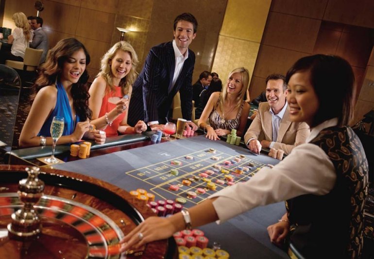 Красивые девушки и парни за игрой в рулетку в престижном казино