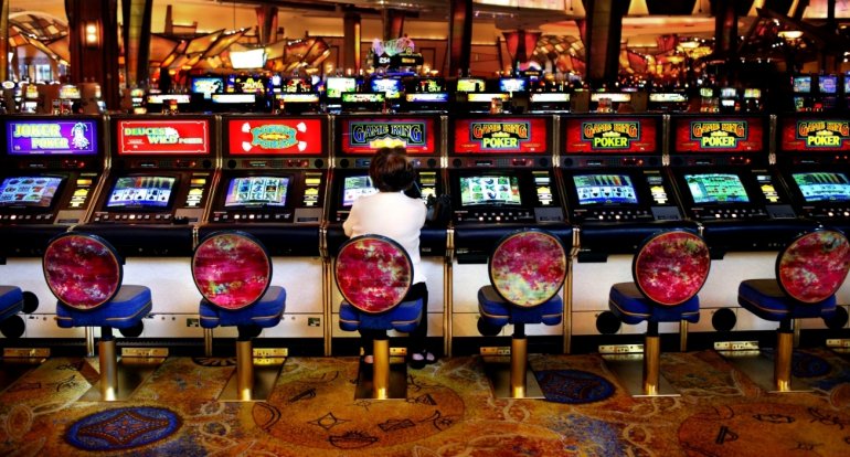 Ряд автоматов с видео покером, по середине которого сидит женщина