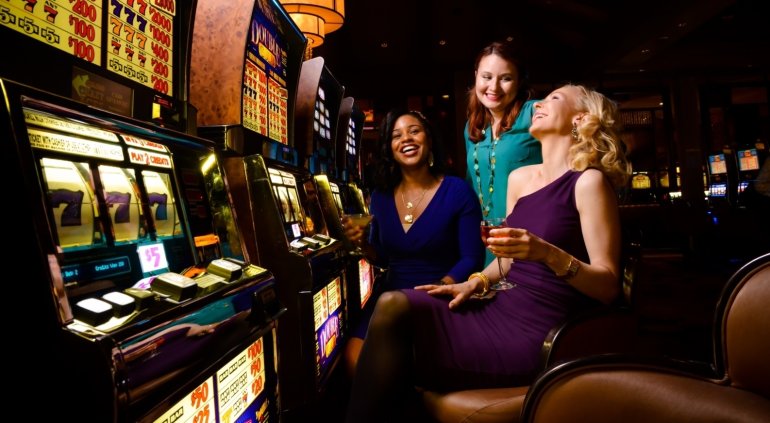 Три азартных подруги весело проводят время за игровыми автоматами в казино