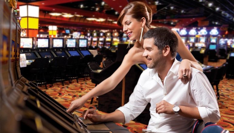 Мужчина играет в видео покер, а женщина обнимает его за плечи