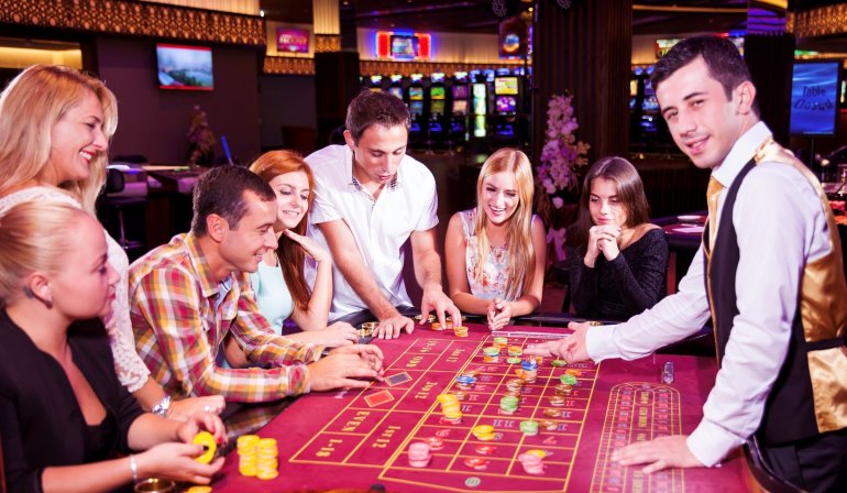 Молодой крупье грузин ведет игру в рулетку для элитных клиентов казино