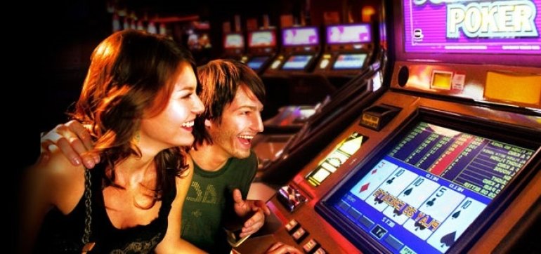 Мужчина и женщина за игрой в видео покер в зале казино