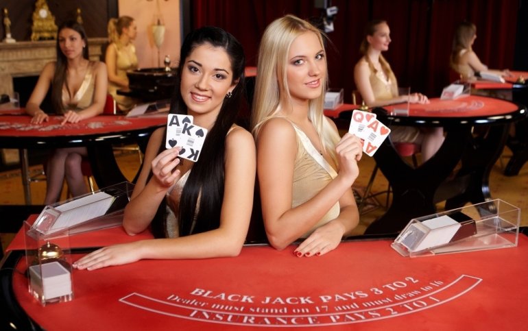Две красотки-дилеры казино, блондинка и брюнетка, позируют с картами за столом для блэкджека
